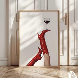 May include: A framed print of a pair of red boots with a glass of red wine balanced on top of one of the boots.