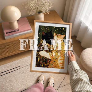 May include: A framed art print depicting two cats in a Klimt-inspired style. The image shows a black cat and a ginger cat, with gold and patterned elements. The frame is light wood. The text "FRAME MOCKUP" is overlaid on the image.