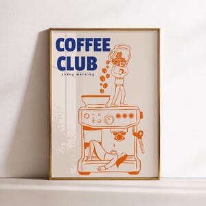 May include: A framed wall art print featuring a beige background with blue text that reads COFFEE CLUB every morning. An orange line drawing depicts a person pouring coffee beans into a machine while another person rests underneath it.