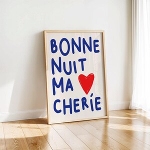 May include: A framed print with the text "BONNE NUIT MA CHERIE" in blue lettering and a red heart. The background is white.