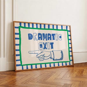 May include: A framed rectangular wall art piece featuring a cream background with a blue and white striped border and a green inner frame. The text "DRAMATIC EXIT" is printed in blue, accompanied by a blue line-art illustration of a pointing hand.