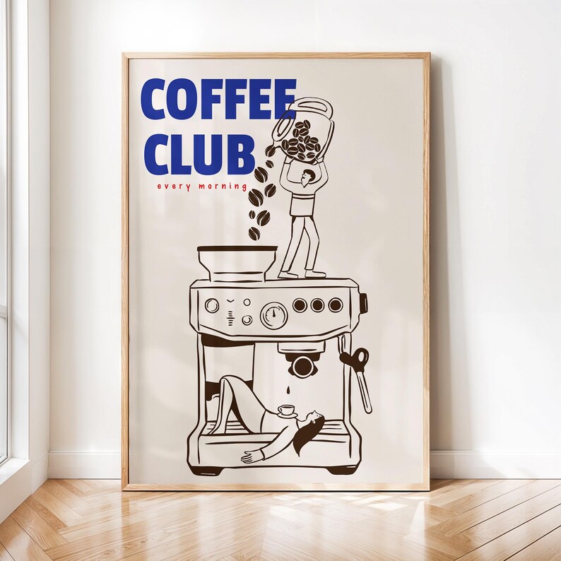 May include: A framed wall art print featuring a beige background with the blue text COFFEE CLUB and red text every morning. A line drawing shows a person pouring coffee beans into a machine while another person rests inside the machine base.