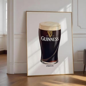 Könnte beinhalten: Gerahmter Druck mit einem Pint Guinness. Das Glas ist mit dunklem Bier gefüllt und mit einem cremigen Schaum bedeckt. Das Guinness-Logo ist deutlich sichtbar. Der Text "Vitamin G" steht unten.