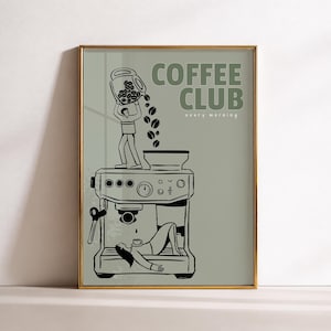 May include: A framed wall art print with a sage green background featuring black line art of a coffee machine. A figure stands on top pouring coffee beans into the machine, while another figure rests underneath. Text reads COFFEE CLUB every morning.