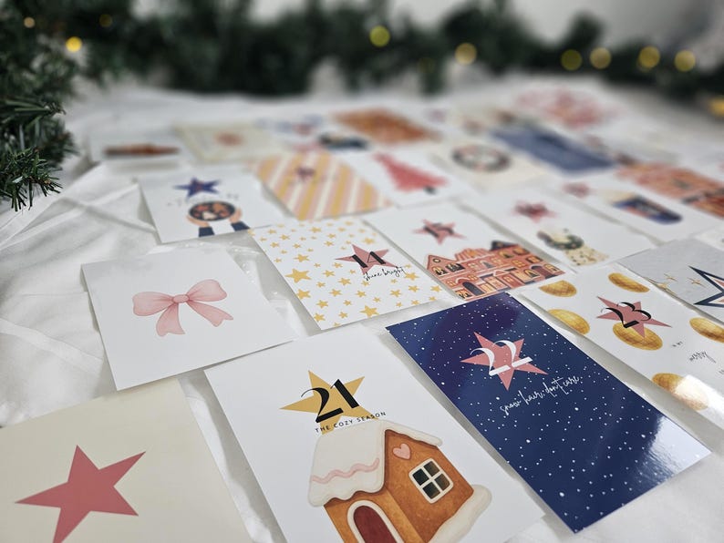 May include: A collection of Christmas-themed cards with various designs, including stars, bows, and gingerbread houses. The cards are arranged on a white surface, with some featuring text like "shine bright" and numbers.