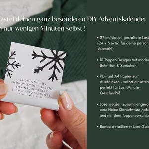 May include: A person holds a white card with black snowflake designs and text. The card is part of a DIY Advent calendar kit. The background includes a green knitted fabric and text in German.