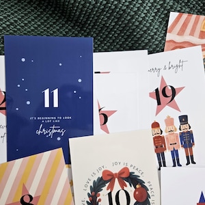 May include: A collection of Christmas-themed cards with various designs. One card is navy blue with the number 11 and the text "It's beginning to look a lot like Christmas." Other cards feature stars, gift boxes, and illustrations.