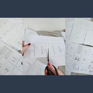 K&ouml;nnte beinhalten: Mehrere Bl&auml;tter wei&szlig;es Papier mit schwarzer Strichzeichnung und Text bedruckt. Eine Schere schneidet ein Blatt. Die Designs umfassen Geschenkkarten-Vorlagen, Illustrationen und S&auml;tze wie "Be Happy" und "Soft Care for Art".