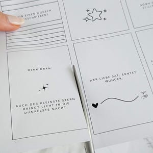 May include: A sheet of white paper with inspirational quotes and illustrations, including stars, hearts, and a sprout. The paper is being cut with scissors. The text includes phrases like "Think about it" and "Love is enough."