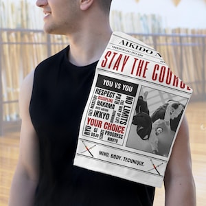 Może przedstawiać: Biały ręcznik z czerwonymi napisami "AIKIDO N" i "STAY THE COURSE". Ręcznik przedstawia czarno-biały obraz praktyków Aikido i różne terminy Aikido. Widoczny jest również tekst "YOURSPIRITART.ETSY.COM".