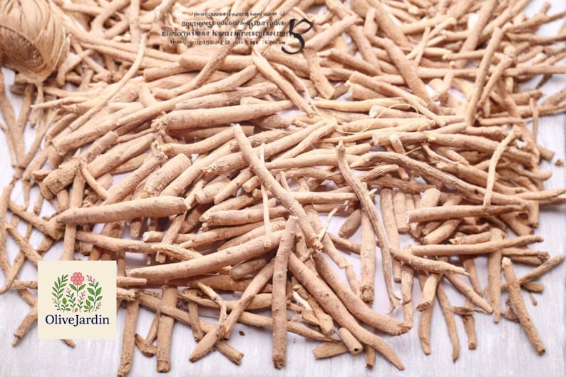 May include: A pile of light brown, dried ashwagandha roots. The image includes a ball of twine in the upper left corner and the OliveJardin logo in the lower left corner. The roots are of varying lengths and thicknesses.