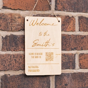 May include: A rectangular wooden sign with the text "Welcome to the Smith's" in a script font. Below, it reads "HOME IS WHERE THE WIFI IS" and "NETWORK PASSWORD". A QR code is also present.