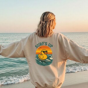 Surf&#39;s Up Duck Sweatshirt – Funny Beach Crewneck with Retro Sunset & Rubber Duck | Oversized Surf Gift for Ocean Lovers