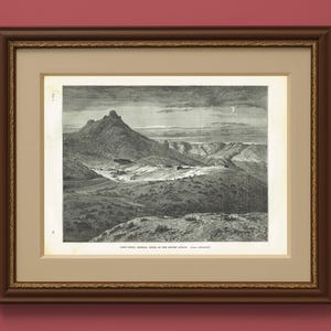 Puede incluir: Impresión en blanco y negro enmarcada de un paisaje que representa una cordillera y un valle. La impresión está en un marco de madera marrón con un passe-partout color crema. La impresión se titula "FORT BROWN, ARIZONA, SCENE OF THE APACHE ATTACK."