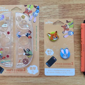 以下が含まれることがあります： ディズニー映画「ズートピア」をテーマにしたNintendo Switchアクセサリーのセット。 青とオレンジのアクセントが付いた2つの黒いコントローラー、キャラクターグラフィック付きの透明保護カバー、スティックカバーが含まれています。