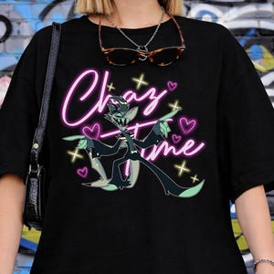 May include: Black t-shirt with the words "Crazy Time" in pink neon script, featuring a cartoon character with green and black accents, surrounded by hearts and stars. The shirt is worn by a person.