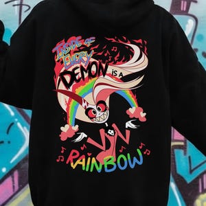May include: Black hoodie with a colorful graphic on the back. The graphic features a cartoon character with a rainbow, musical notes, and the text "Inside of Every Demon is a Rainbow."