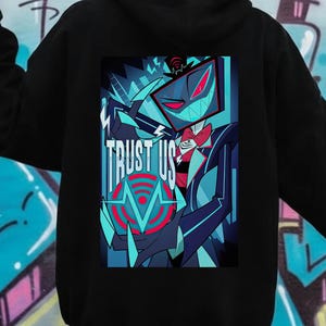 May include: Black hoodie featuring a vibrant graphic on the back. The graphic includes a stylized character with a screen-like face, set against a dark blue and teal background. The text "TRUST US" is prominently displayed.