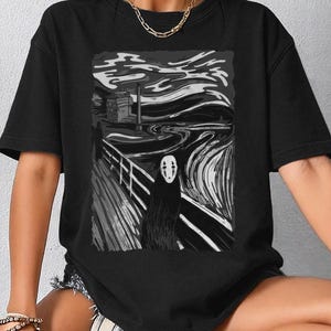Op de afbeelding: Zwart t-shirt met een zwart-witte grafische print. De afbeelding toont een gestileerd landschap met een figuur die doet denken aan No-Face uit Spirited Away. Het woord "BLACK" staat bovenaan gedrukt.