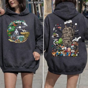 May include: Dark grey hoodie with a front pocket and hood. The front has a colourful illustration of characters and scenes. The back of the hoodie displays a detailed graphic of a castle and various animated figures.