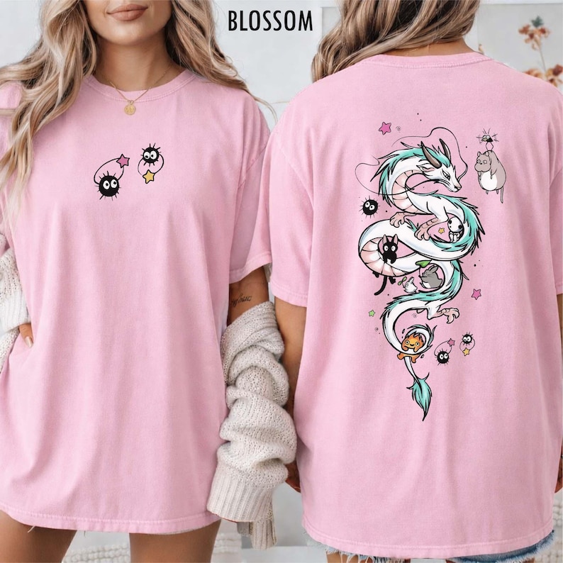 Pode incluir: T-shirts rosa com design de desenho animado. Uma camisa apresenta um drag&atilde;o com um design turquesa e branco nas costas. A outra camisa tem um design de desenho animado na frente. A palavra "BLOSSOM" &eacute; impressa no topo.