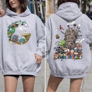 May include: Sport grey hoodie with front and back graphic designs. The front has a circular illustration with a dragon and characters. The back shows a detailed image of a castle and animated figures. The hoodie features a front pocket and a hood.