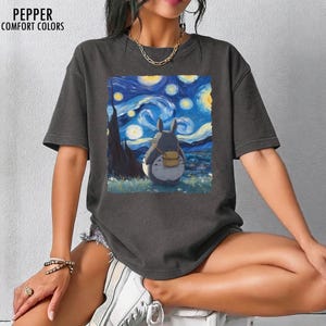 May include: Dark grey t-shirt featuring a graphic of Totoro from My Neighbor Totoro, with a backdrop inspired by Van Gogh's "Starry Night." The shirt has the text "PEPPER COMFORT COLORS" at the top left.
