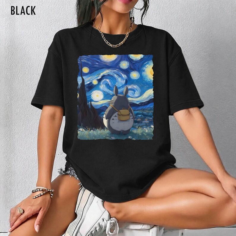 May include: Black t-shirt featuring a graphic of Totoro from My Neighbor Totoro, set against a backdrop inspired by Van Gogh's "Starry Night." The image includes a gray Totoro with a yellow backpack, under a swirling blue and yellow sky.