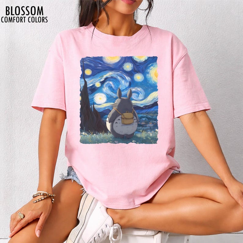 May include: Pink t-shirt with a graphic of Totoro from My Neighbor Totoro, set against a starry night sky in the style of Van Gogh's "Starry Night." The shirt has the text "BLOSSOM COMFORT COLORS" at the top left.