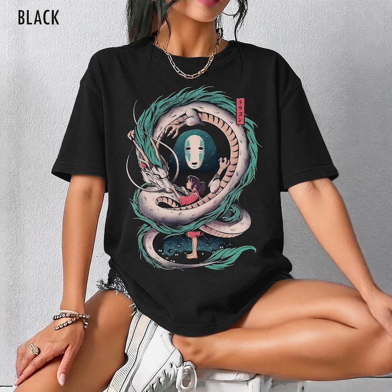 May include: Black t-shirt featuring a colorful illustration of a dragon, a girl, and a masked figure. The dragon is white with green accents, and the girl wears a pink top. Japanese text is in a red box. The word "BLACK" is at the top.