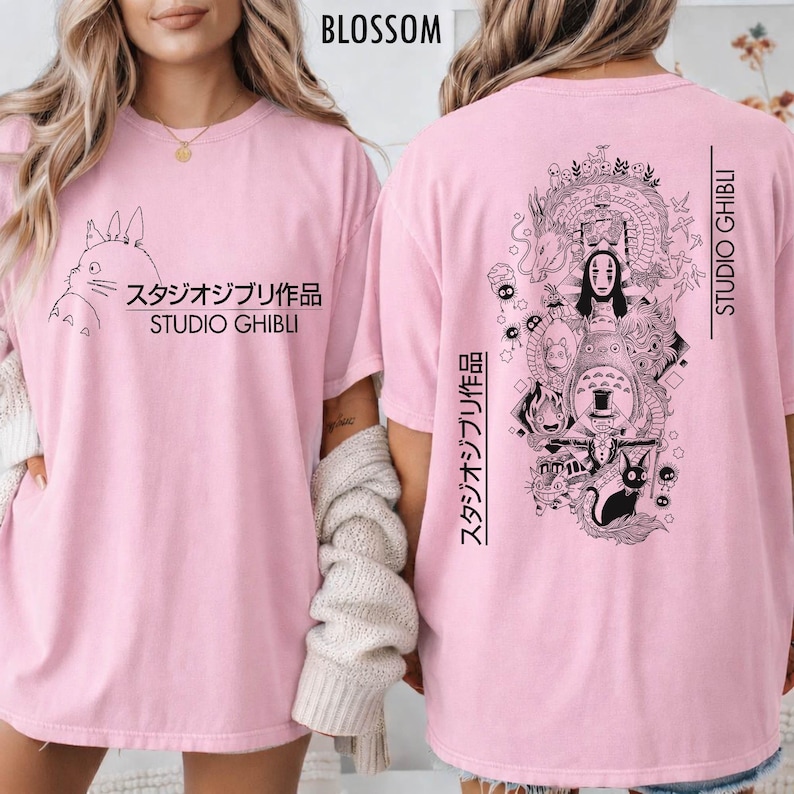 May include: Light pink t-shirts with black Studio Ghibli graphics. The front features a Totoro design with Japanese text and "Studio Ghibli." The back displays a detailed illustration of various Ghibli characters and text.