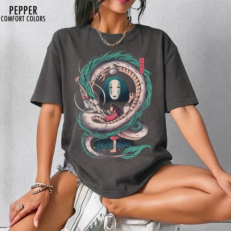 May include: Dark gray t-shirt featuring a Spirited Away graphic. The design includes a white dragon with teal accents, a girl in a red dress, and a character with a white mask. The text "Pepper Comfort Colors" is at the top left.