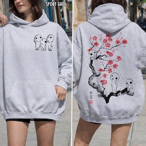 May include: Sport grey hoodie with a front pocket and a hood. The front features a black graphic of three small figures. The back displays a tree with red flowers and more figures, with Japanese text.