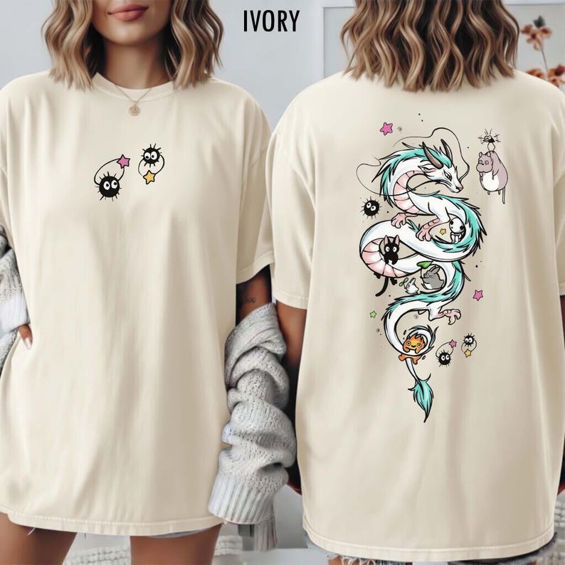 Pode incluir: Camiseta de cor marfim com um design extravagante. A frente apresenta duas personagens de desenhos animados, enquanto a parte de tr&aacute;s exibe uma ilustra&ccedil;&atilde;o detalhada de um drag&atilde;o com detalhes azuis e brancos, acompanhada por outras figuras animadas. Uma pe&ccedil;a de roupa confort&aacute;vel e casual.