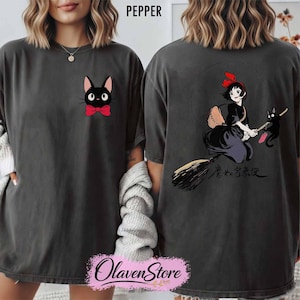 May include: Dark grey t-shirt featuring a black cat with a red bow tie on the front. The back of the shirt displays a graphic of a witch on a broom with a black cat and Japanese text. The word "PEPPER" is printed at the top.