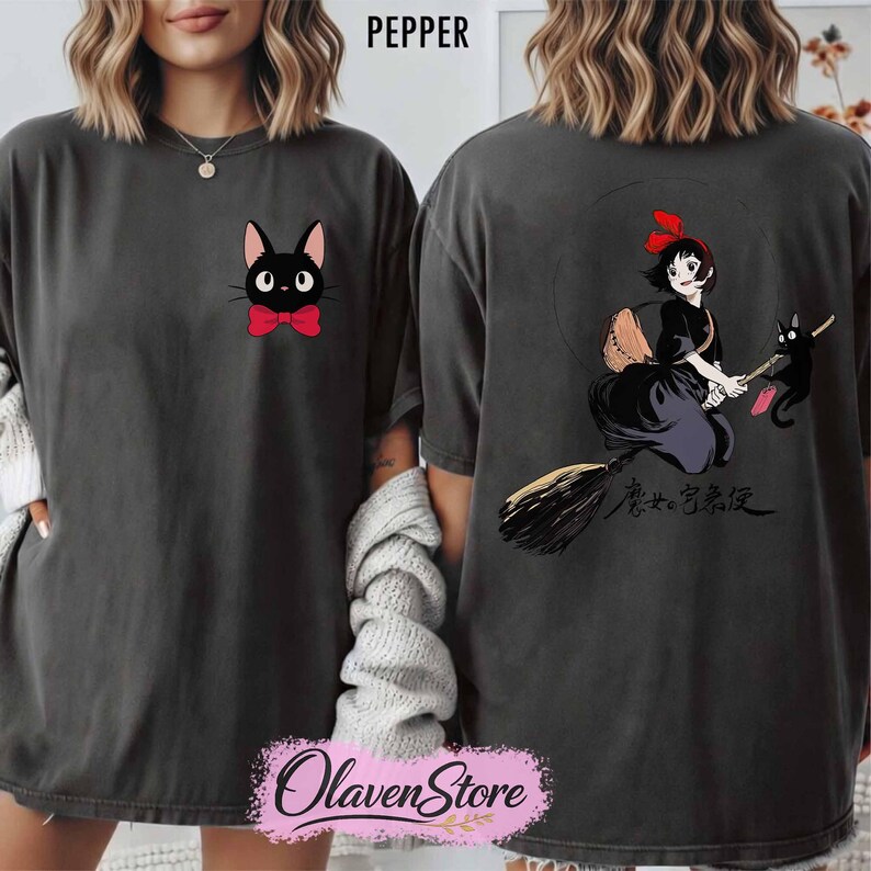 May include: Dark grey t-shirt featuring a black cat with a red bow tie on the front. The back of the shirt displays a graphic of a witch on a broom with a black cat and Japanese text. The word "PEPPER" is printed at the top.