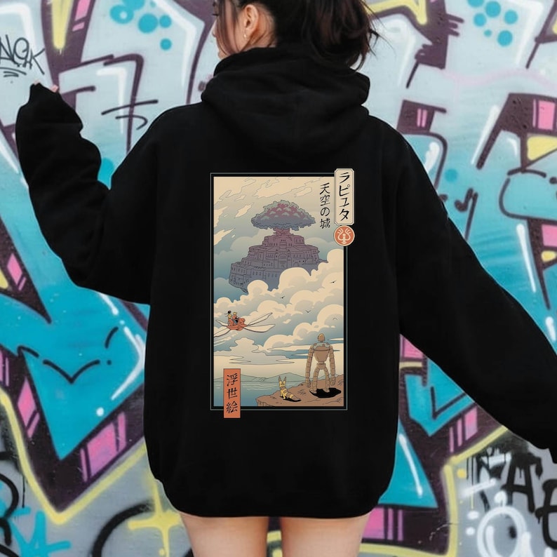 May include: Black hooded sweatshirt with a graphic from the anime film "Castle in the Sky." The design features a floating island, characters, and Japanese text. The sweatshirt is a casual, comfortable style.