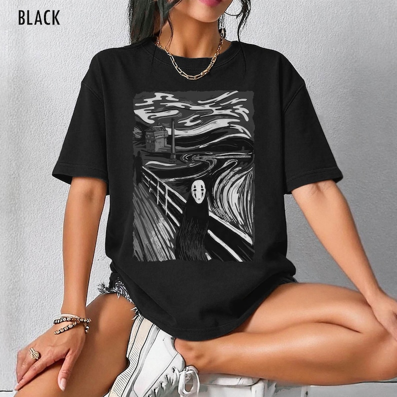 Op de afbeelding: Zwart t-shirt met een zwart-witte grafische print. De afbeelding toont een gestileerd landschap met een figuur die doet denken aan No-Face uit Spirited Away. Het woord "BLACK" staat bovenaan gedrukt.
