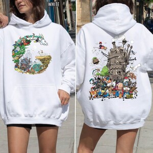 May include: White hoodie with vibrant illustrations from animated films. The front features a circular design with a dragon and characters. The back displays a detailed image of a castle and various characters. A comfortable, casual style.