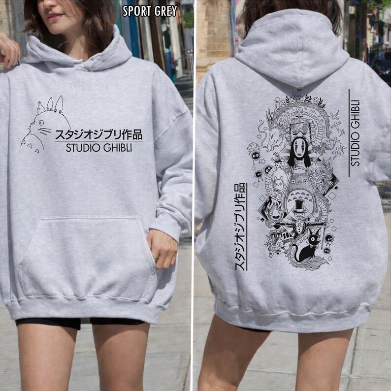 May include: Sport grey hoodie featuring a front graphic of a cartoon character and Japanese text, "スタジオジブリ作品 STUDIO GHIBLI." The back of the hoodie has a black and white illustration with Japanese text and "STUDIO GHIBLI."