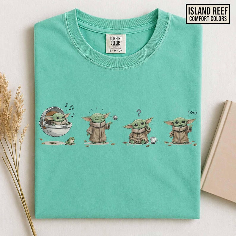 May include: A light teal Comfort Colors t-shirt featuring a graphic of a character from a popular science fiction series. The graphic shows the character in four different poses. The shirt also has the text "Island Reef Comfort Colors".