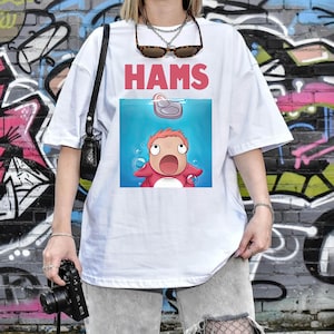 May include: White t-shirt featuring the word "HAMS" in pink above a cartoon image of a character from the animated film Ponyo. The character is in the water, looking upwards with a surprised expression.
