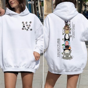 May include: White hoodie featuring a front pocket and a drawstring hood. The front displays a pattern of small, black and white cartoon characters. The back showcases a vertical stack of Studio Ghibli characters with Japanese text and the words "STUDIO GHIBLI".