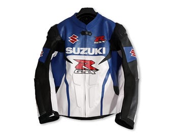 May include: A blue, white, and black motorcycle jacket with the Suzuki and GSX logos. The jacket has a stand-up collar, black accents on the sleeves, and a white front panel. The Suzuki logo is in red and white.