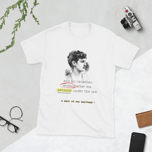 May include: White t-shirt featuring a vintage portrait and text. The text reads "and all canadian women after me, persons under the law, a part of our heritage". The shirt is a short-sleeved crew neck.