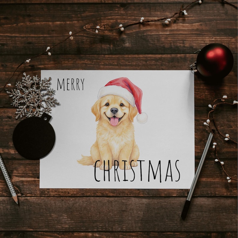May include: A Christmas card with a smiling golden retriever puppy wearing a Santa hat. The words "MERRY CHRISTMAS" are printed above and below the dog illustration. The card is on a wooden surface with decorative elements.