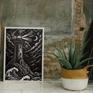 May include: Black and white art print of a lighthouse on a rocky shore under a starry sky. The lighthouse beam shines brightly, with a crescent moon visible. The artwork is framed in white.