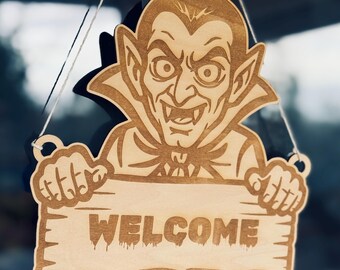 Plik SVG z motywem wampira Dracula i Halloween do wycinania znaków na drzwiach, pliki DXF PDF Ai do ploterów laserowych i grawerów. Personalizowany znak powitalny lub zawieszka na drzwi.