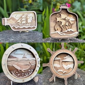 May include: Four wooden nautical-themed decorative pieces. One is a ship in a bottle, another a ship battling a kraken, a third a whale in a porthole, and the last a ship's wheel with a lighthouse. All are layered wood designs.