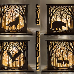 May include: A bundle of four wooden light boxes with forest scenes. Each box features a different silhouette: a wolf howling, a bear with a cub, an eagle in flight, and two deer. The boxes have a warm, glowing interior.